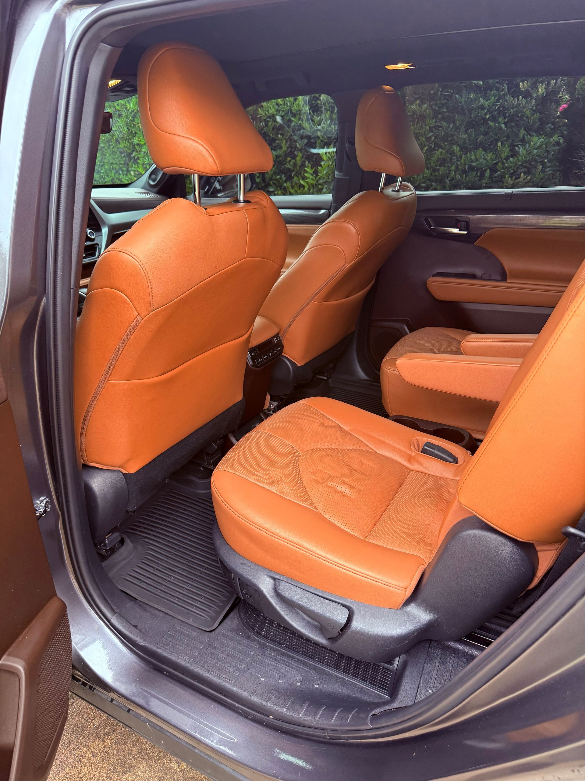Orange leather car interior with rear door open, showing front and back seats.