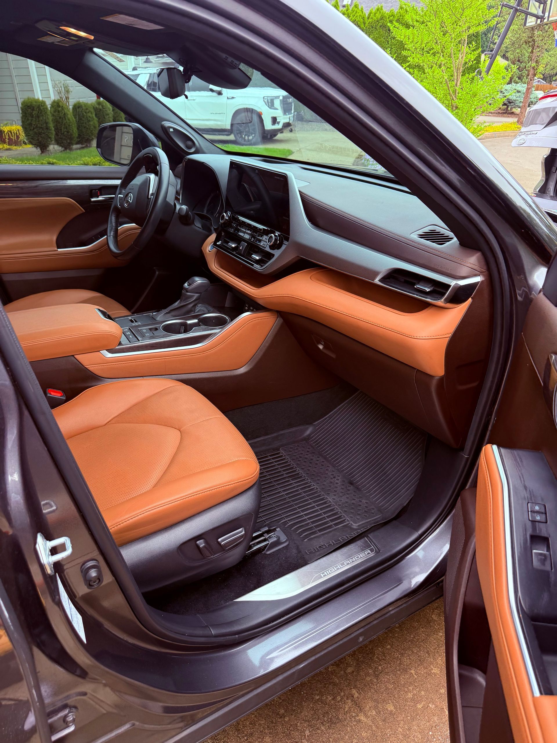 Open car door showing tan leather seats and dashboard with black trim and floor mats