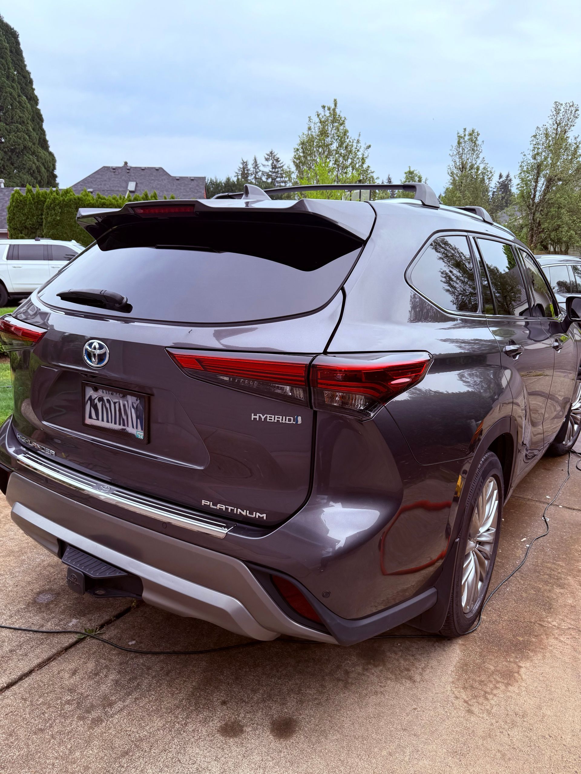 Dark gray SUV parked in a driveway, rear view, with a license plate and wet pavement around it