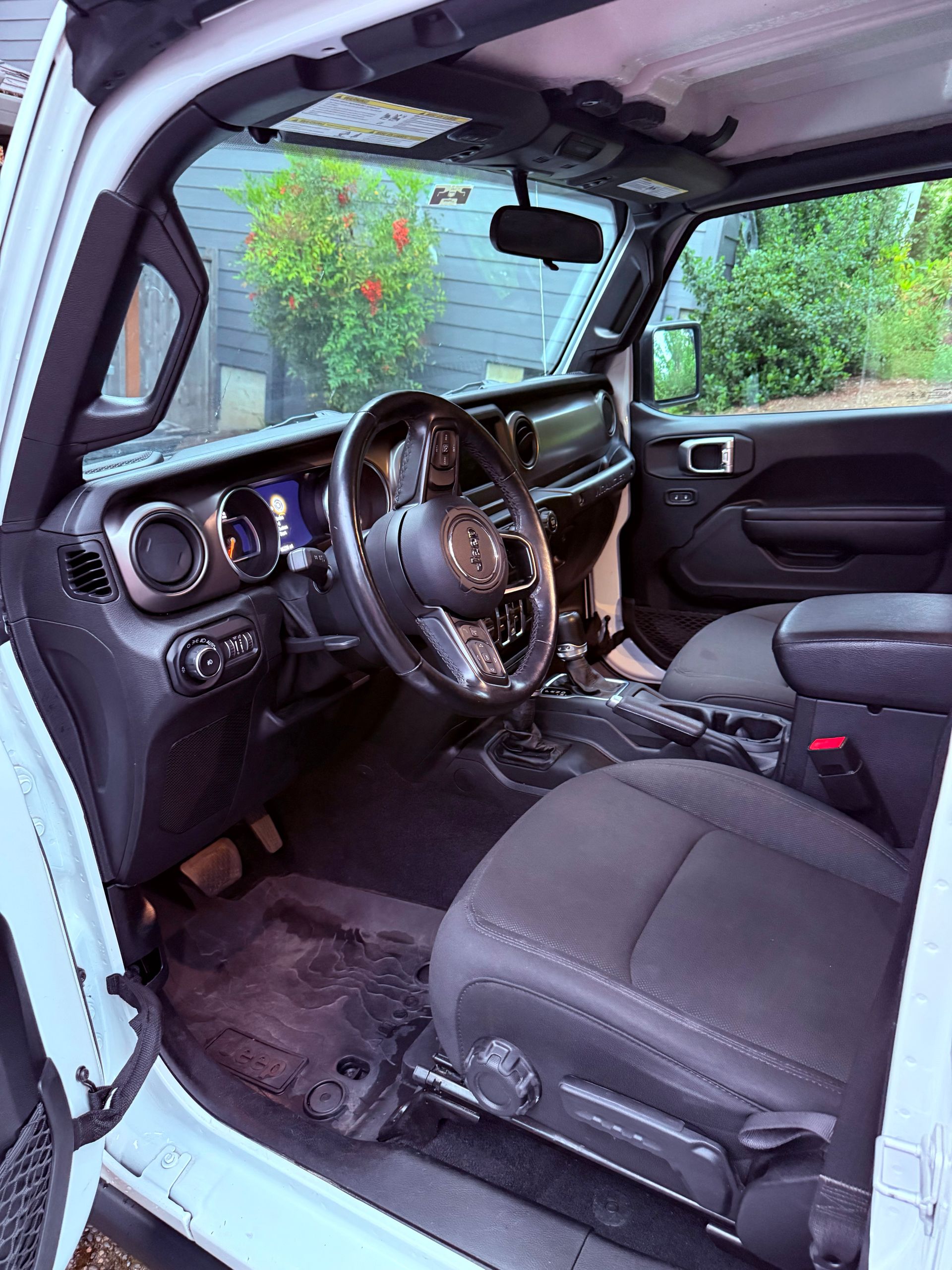 Car interior with front seats, steering wheel, and dashboard, viewed from the open door.