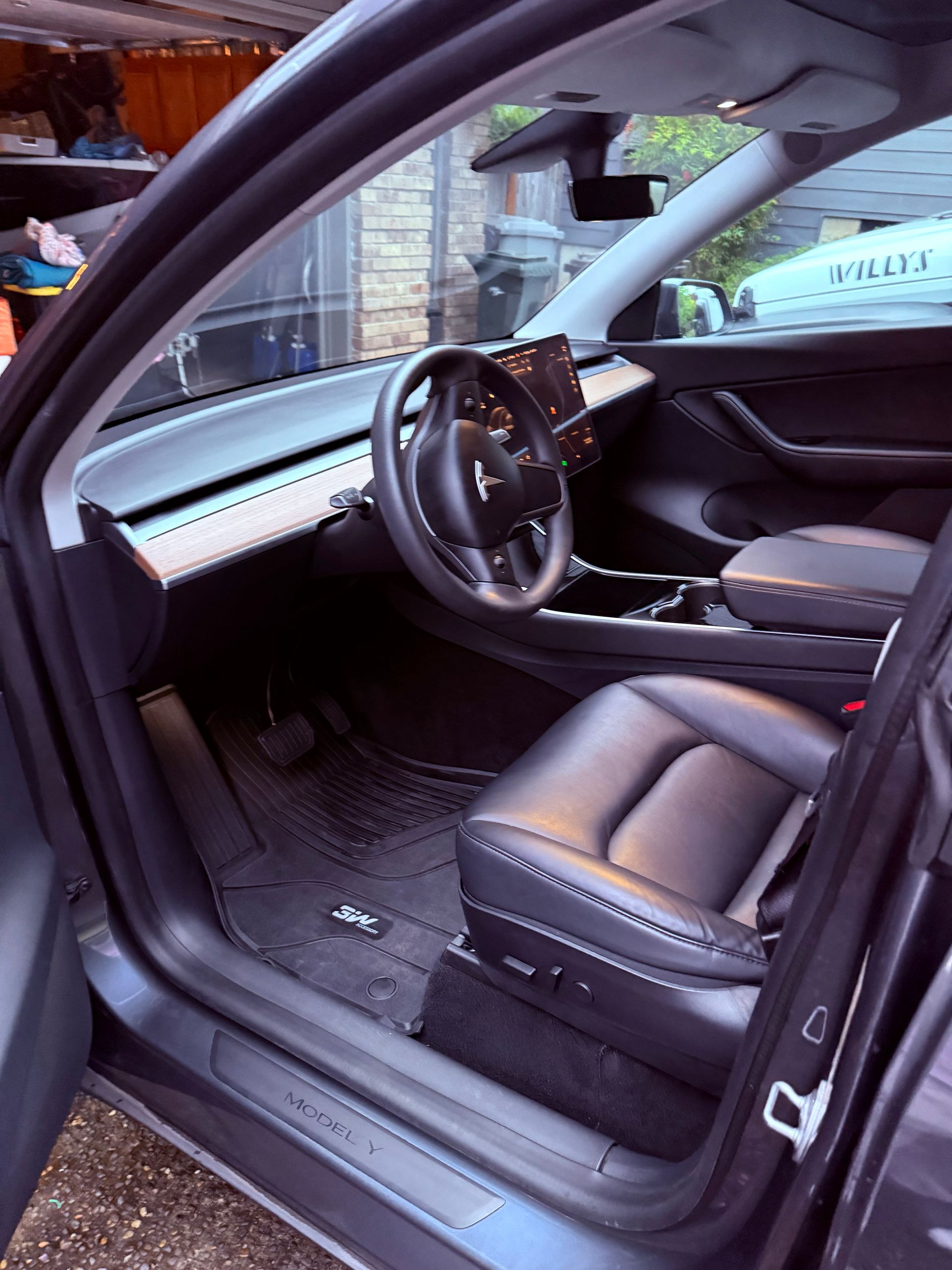 Open car door showing a black leather driver’s seat and steering wheel interior