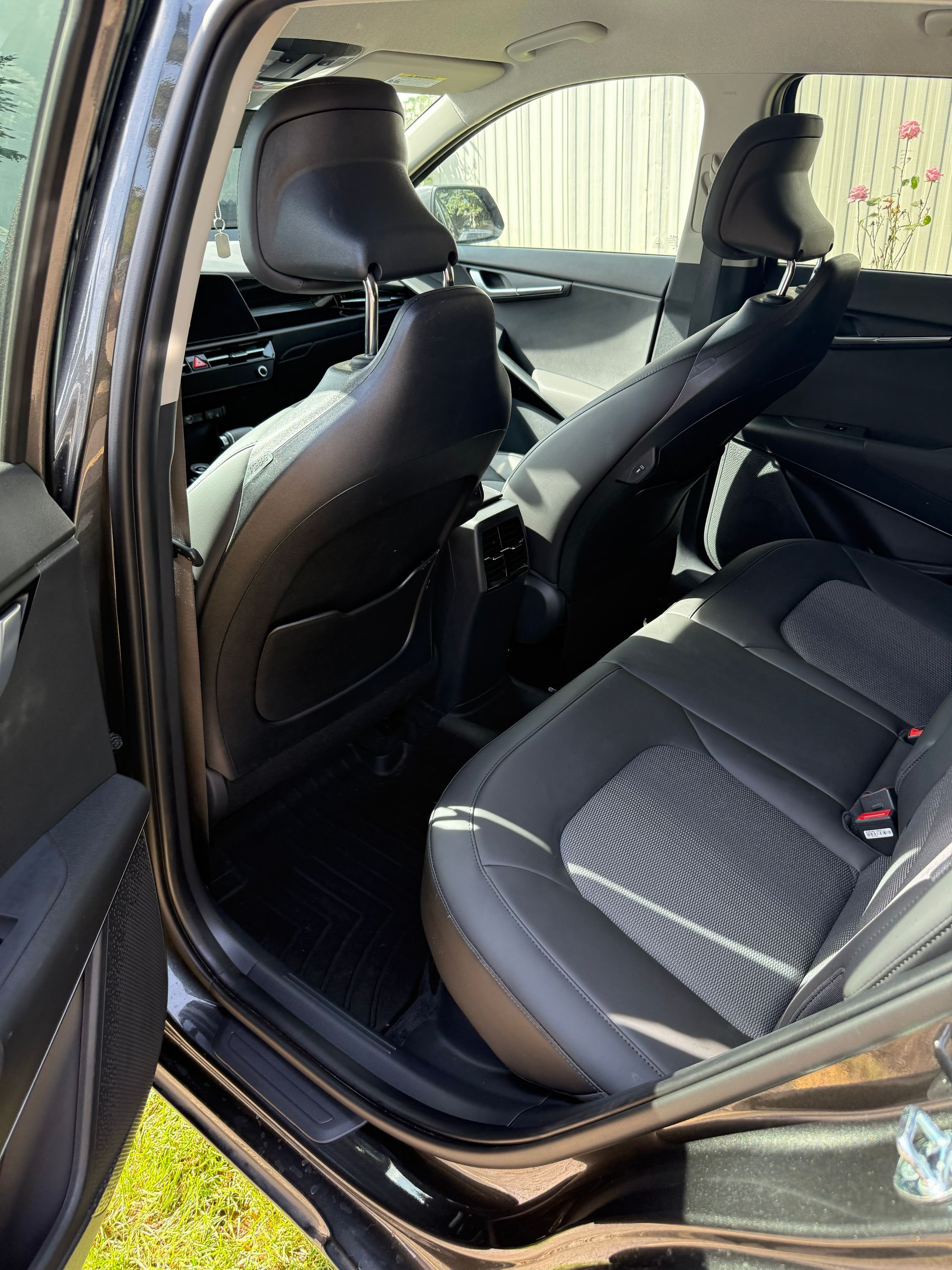 Open car rear passenger area with black fabric seats and the door open.