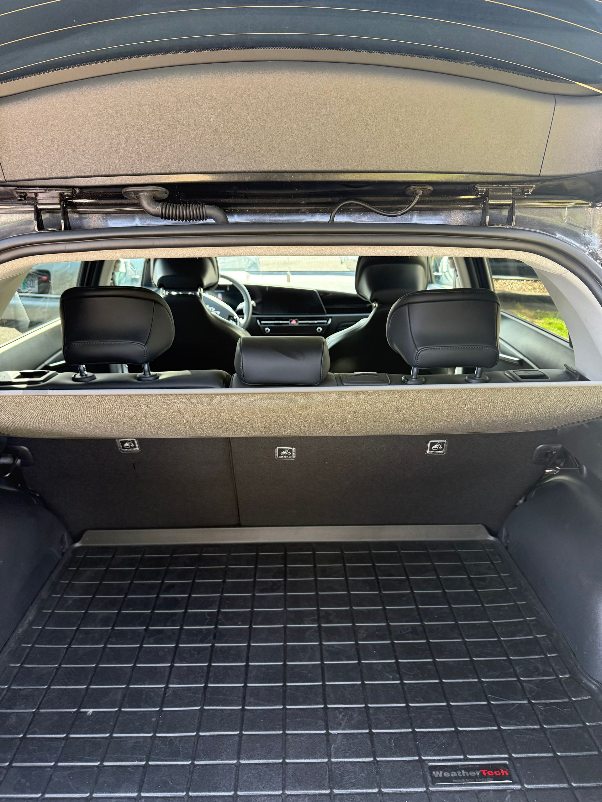 Car trunk open with black cargo mat and rear seats visible under a raised hatch