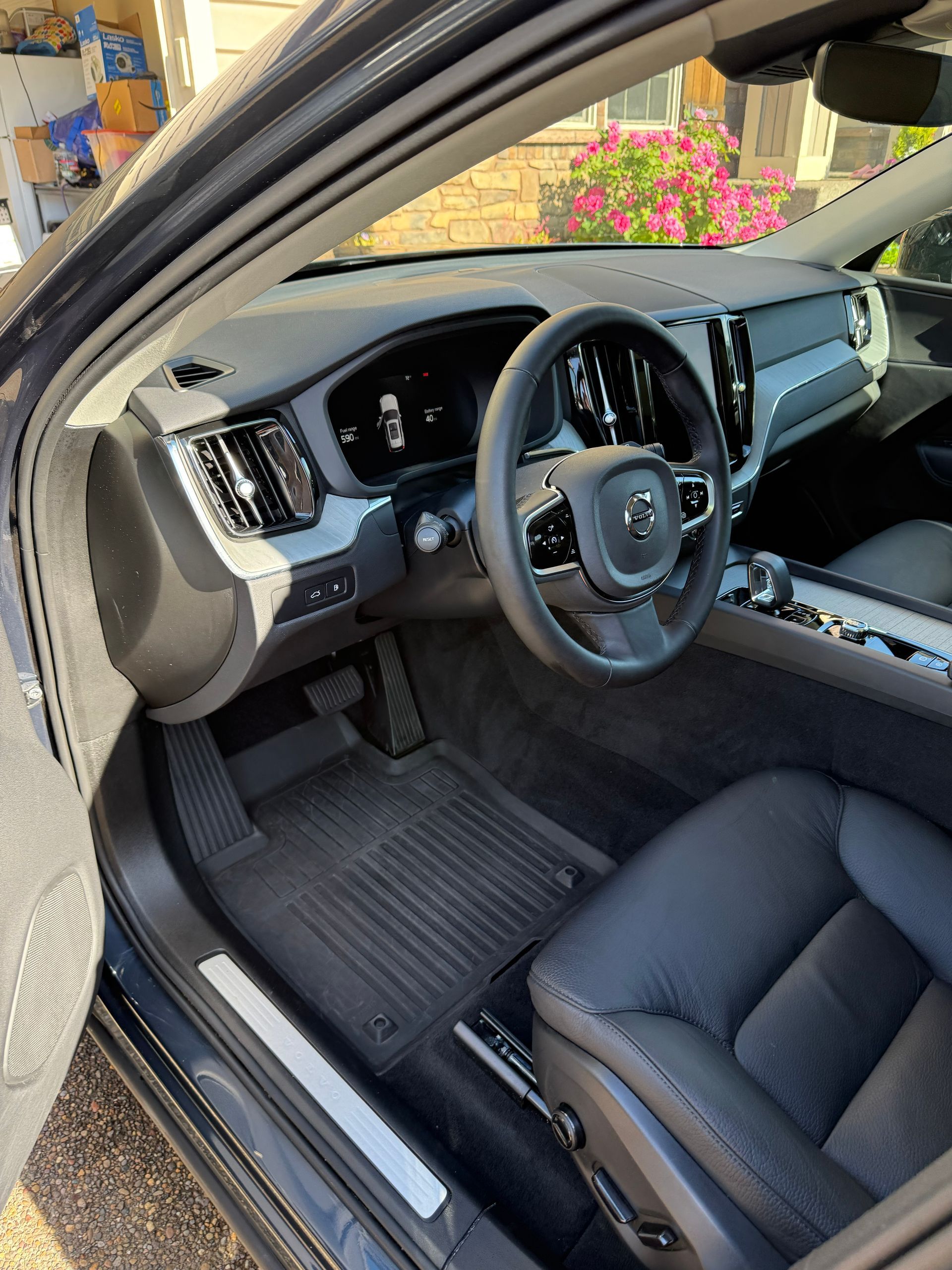 Open car driver’s side with black interior, steering wheel, dashboard, and front seat visible