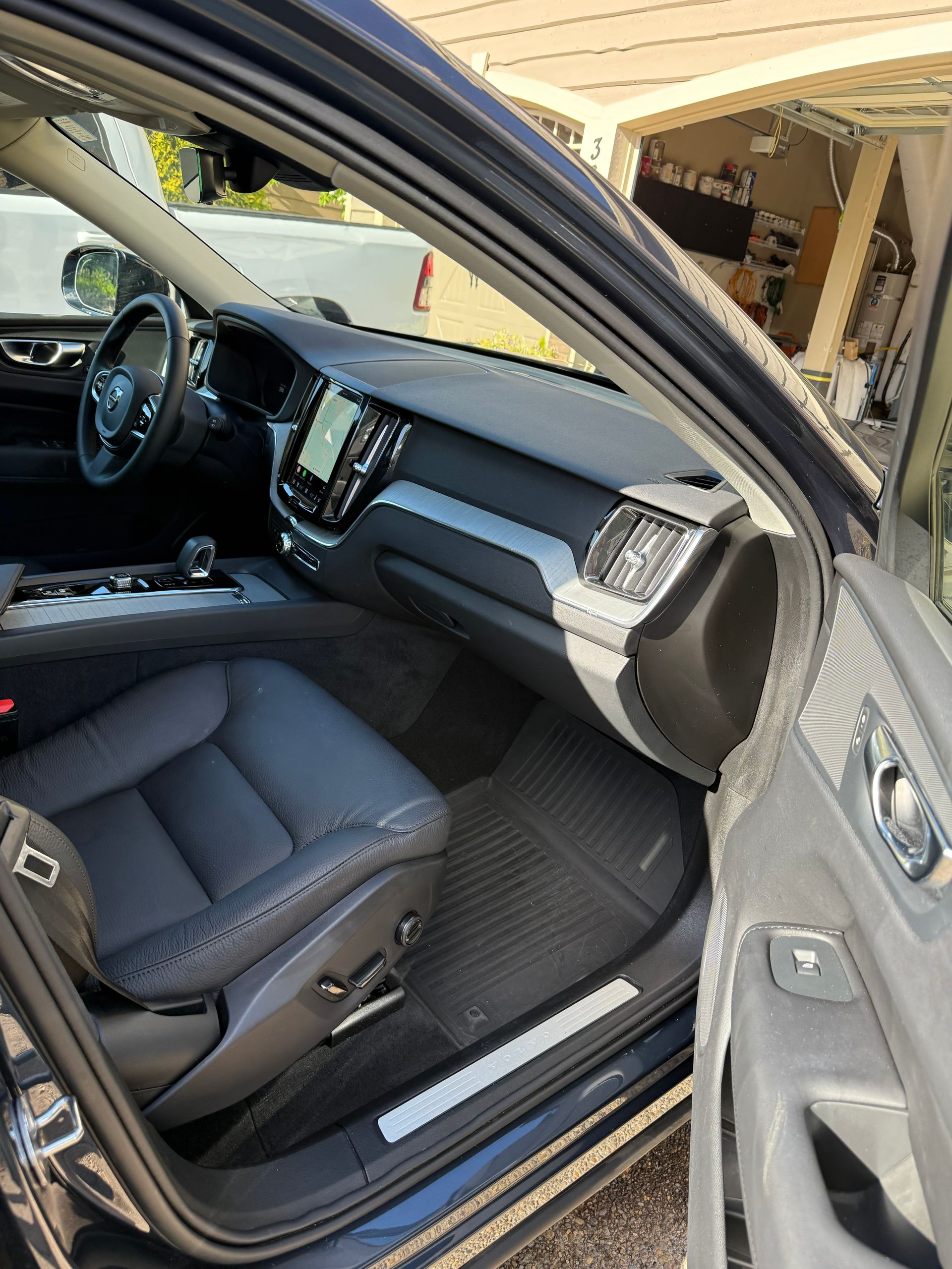 Open car door showing black leather front seat and dashboard inside a vehicle
