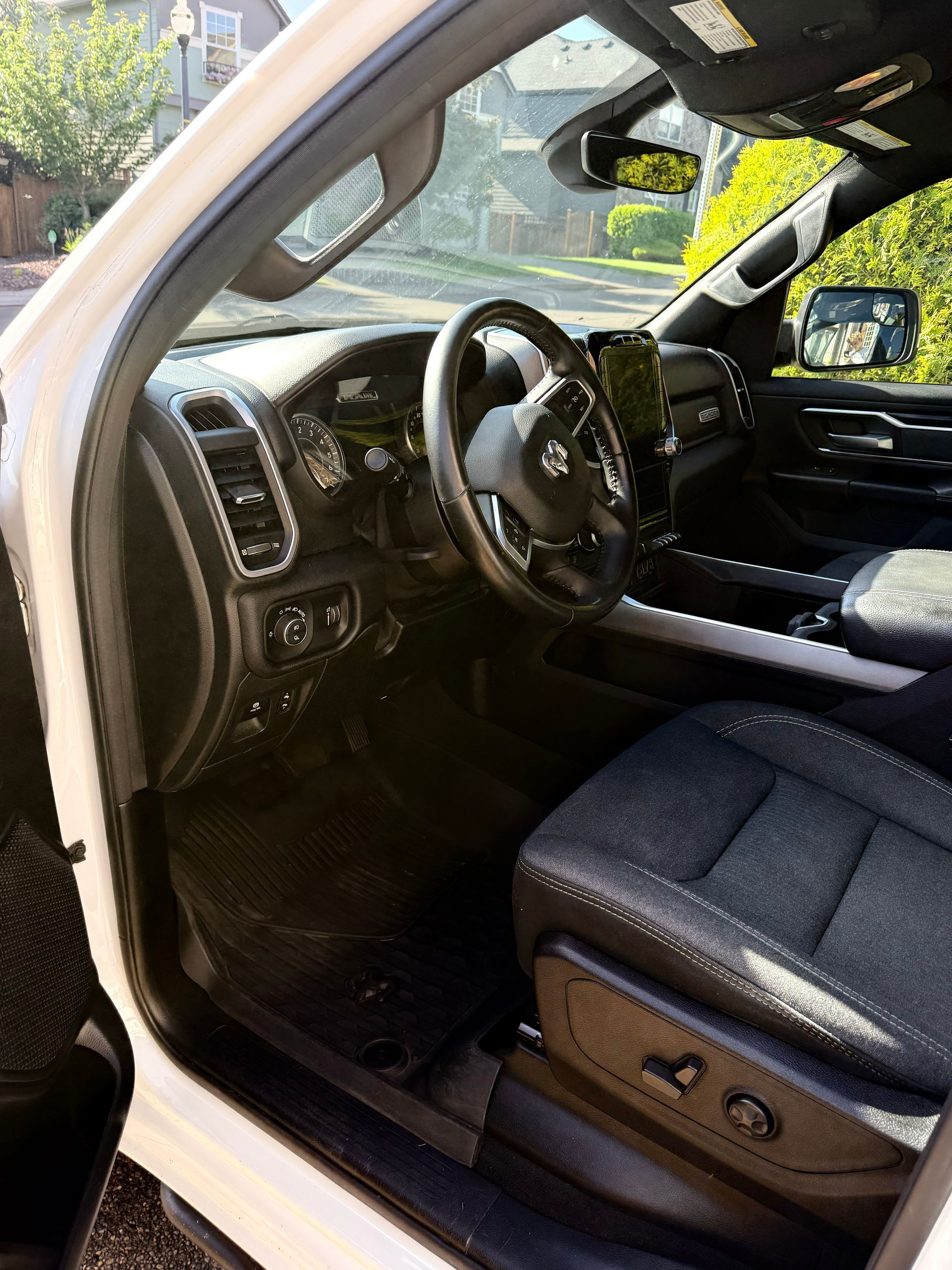 Open driver’s door showing a car’s black interior, steering wheel, dashboard, and front seat.
