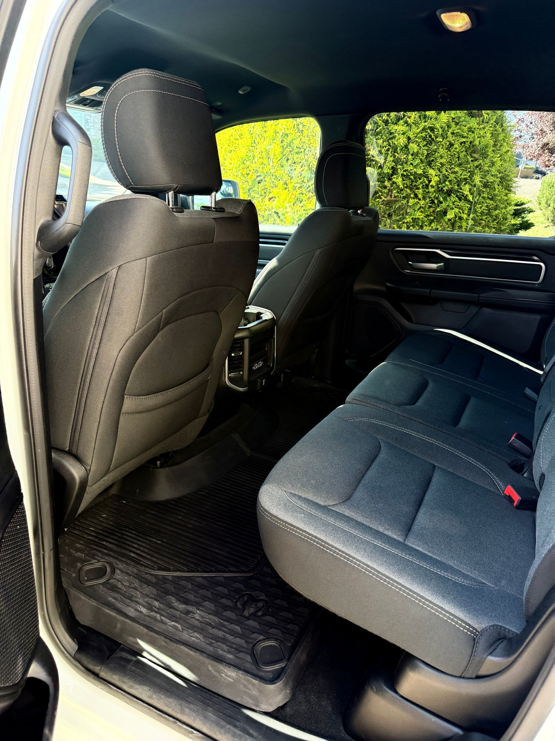 Rear passenger area of a car with black seats and floor mats, viewed from an open door