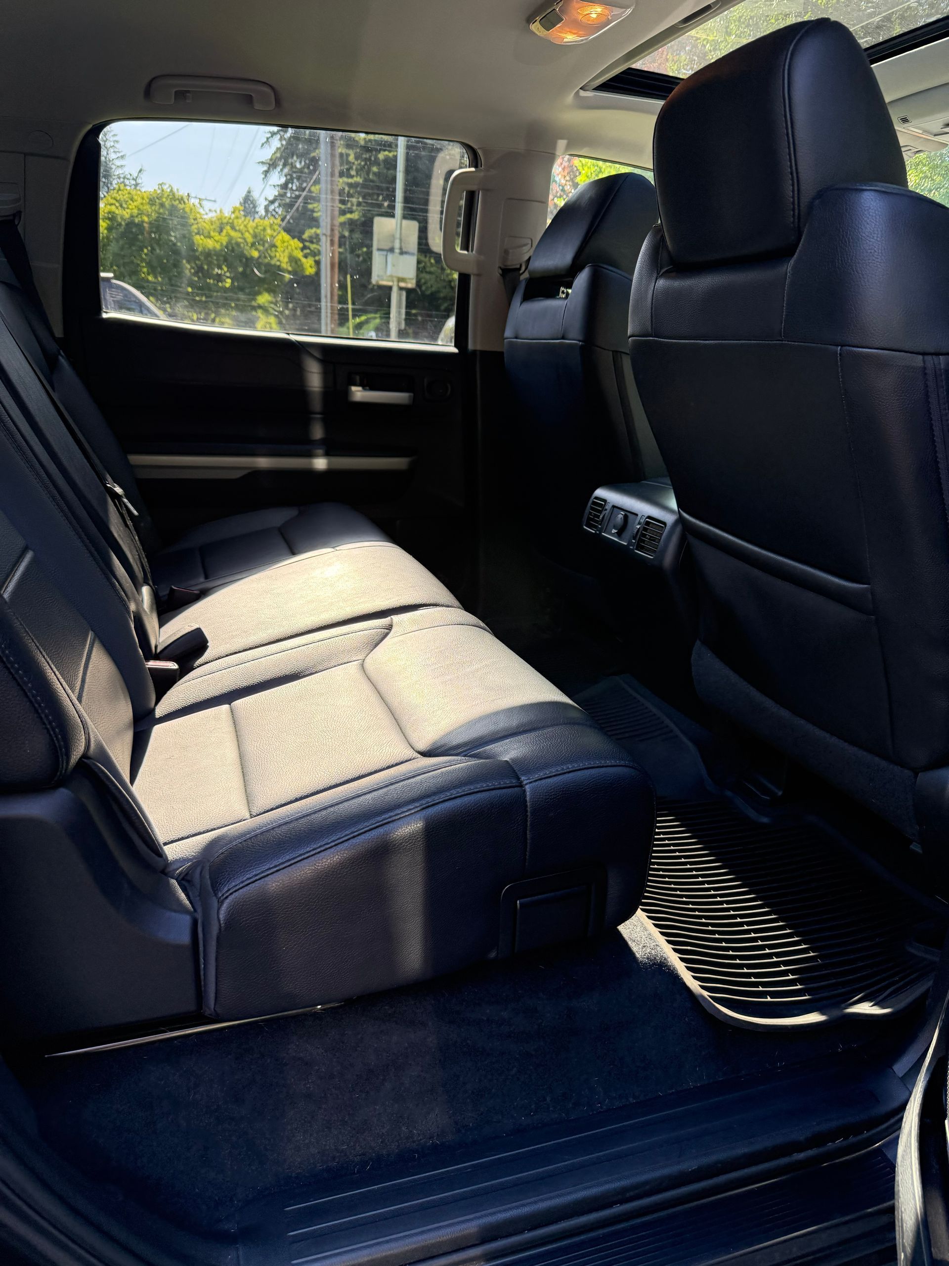 Backseat interior of a vehicle with black seats and sunlight coming through the window