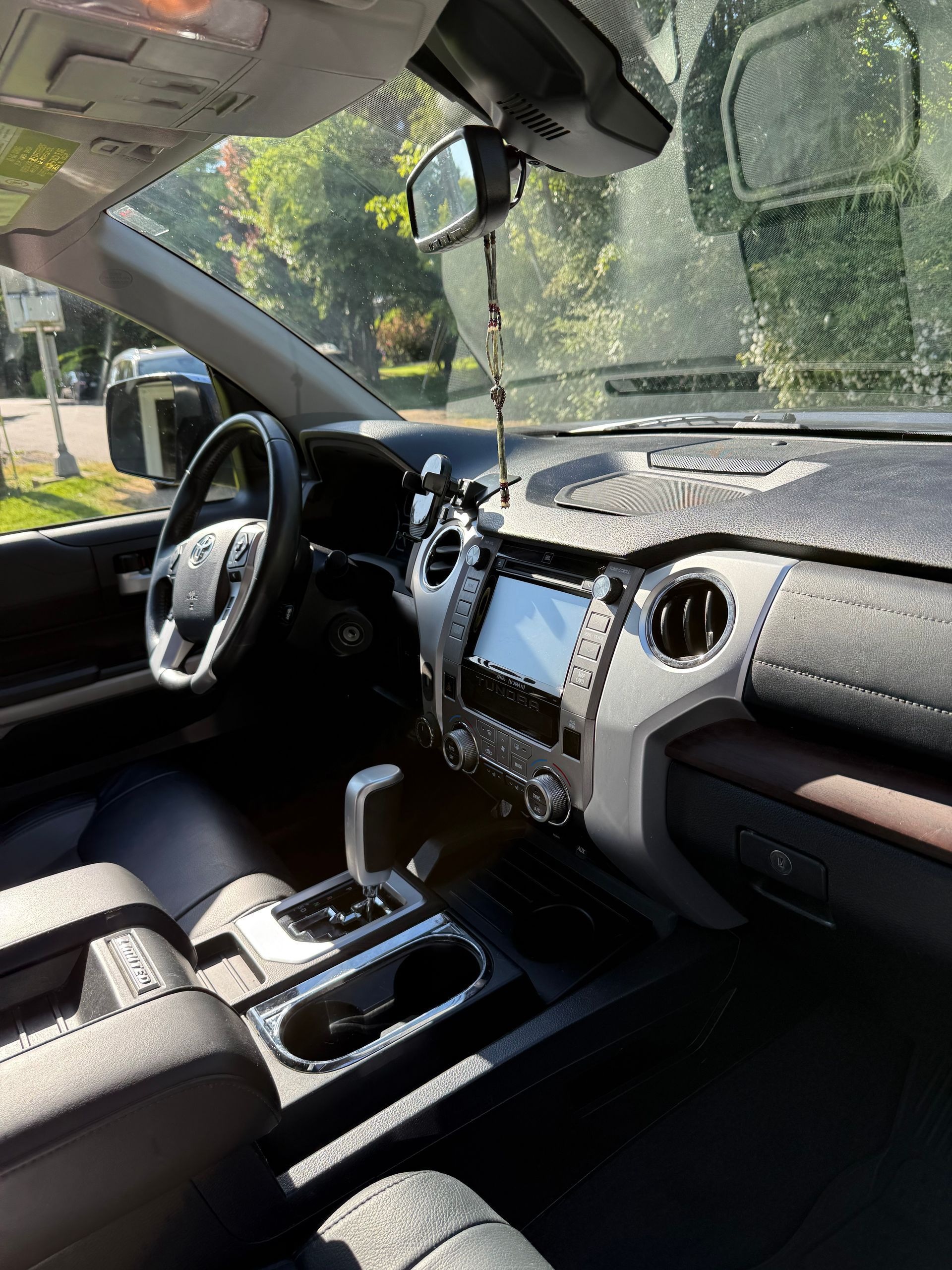 Car interior with black dashboard, center console, and steering wheel; sunlight through the windshield.