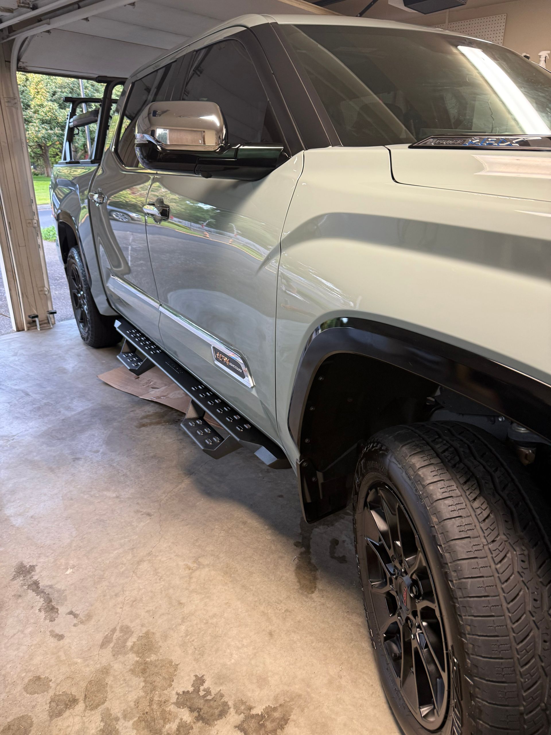 Silver SUV parked in a garage, side view with black wheels and running board