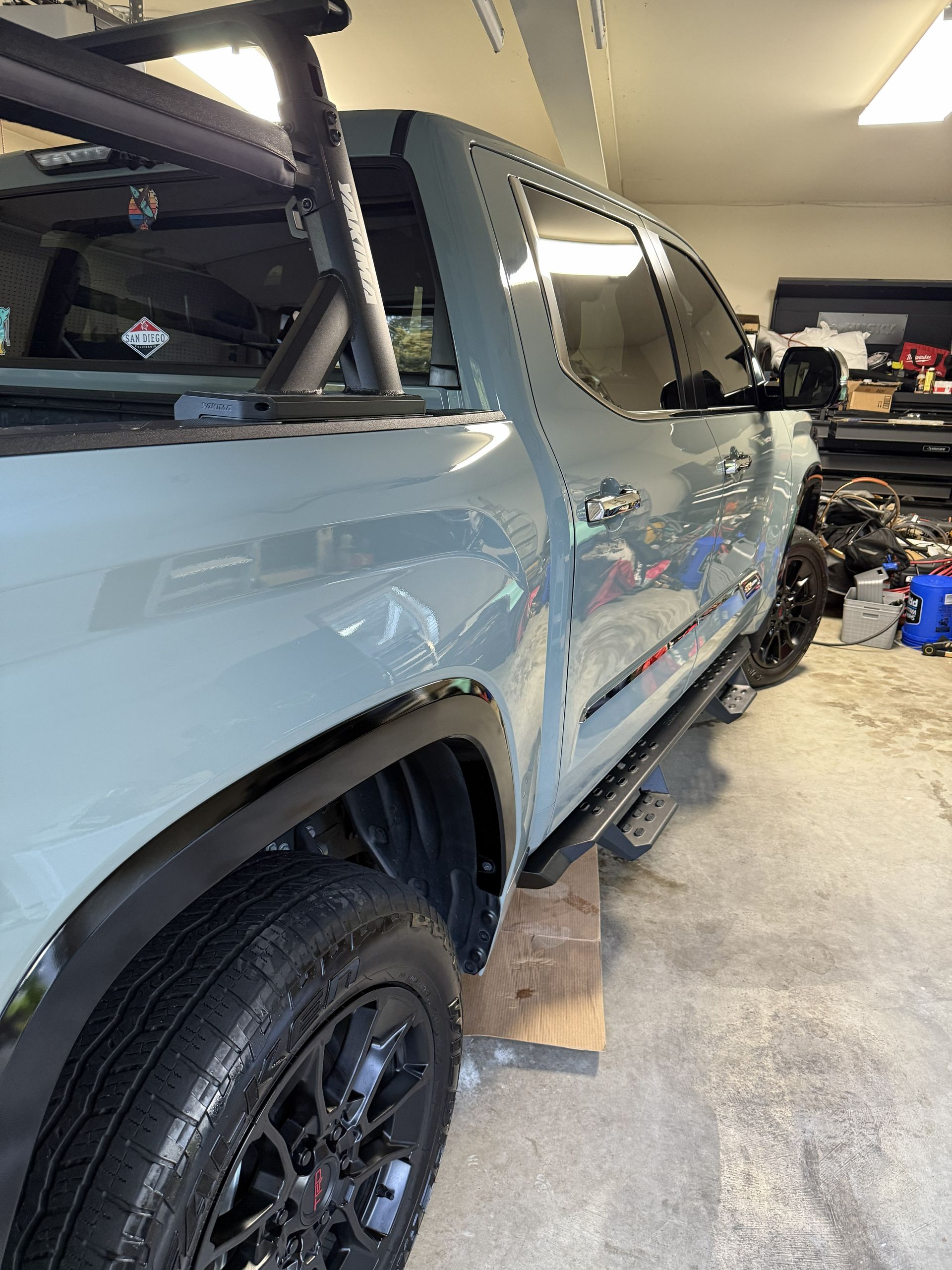 Light blue pickup truck in a garage, shown side view with black wheels and equipment nearby