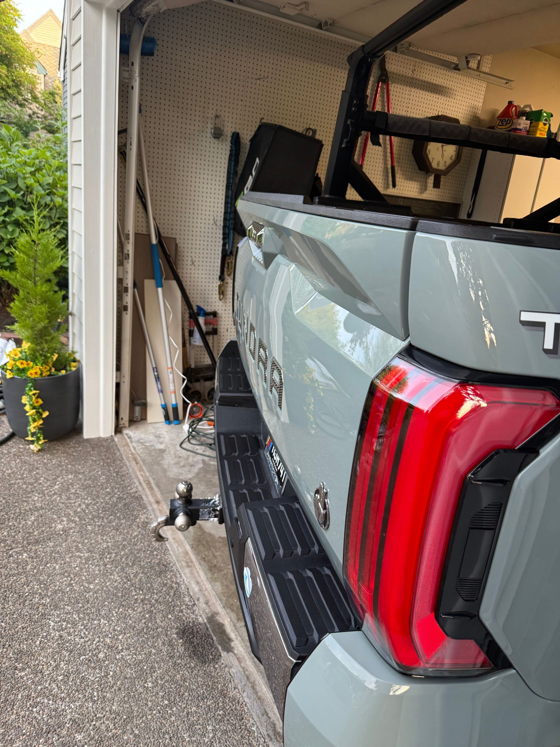 Gray pickup truck backed into a garage, damaging the open garage door and side panel.