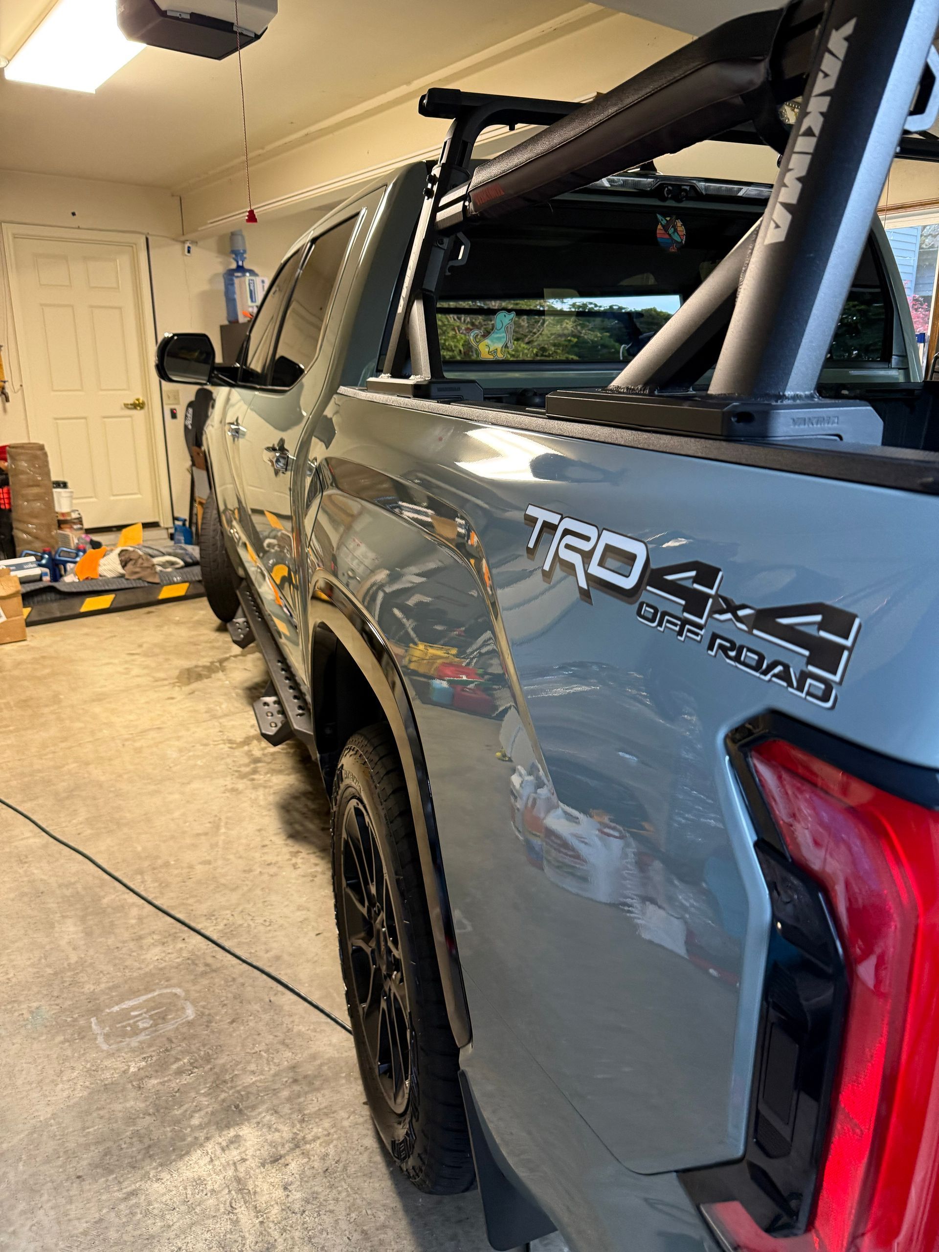 Gray Toyota TRD pickup truck parked in a garage, rear side view.