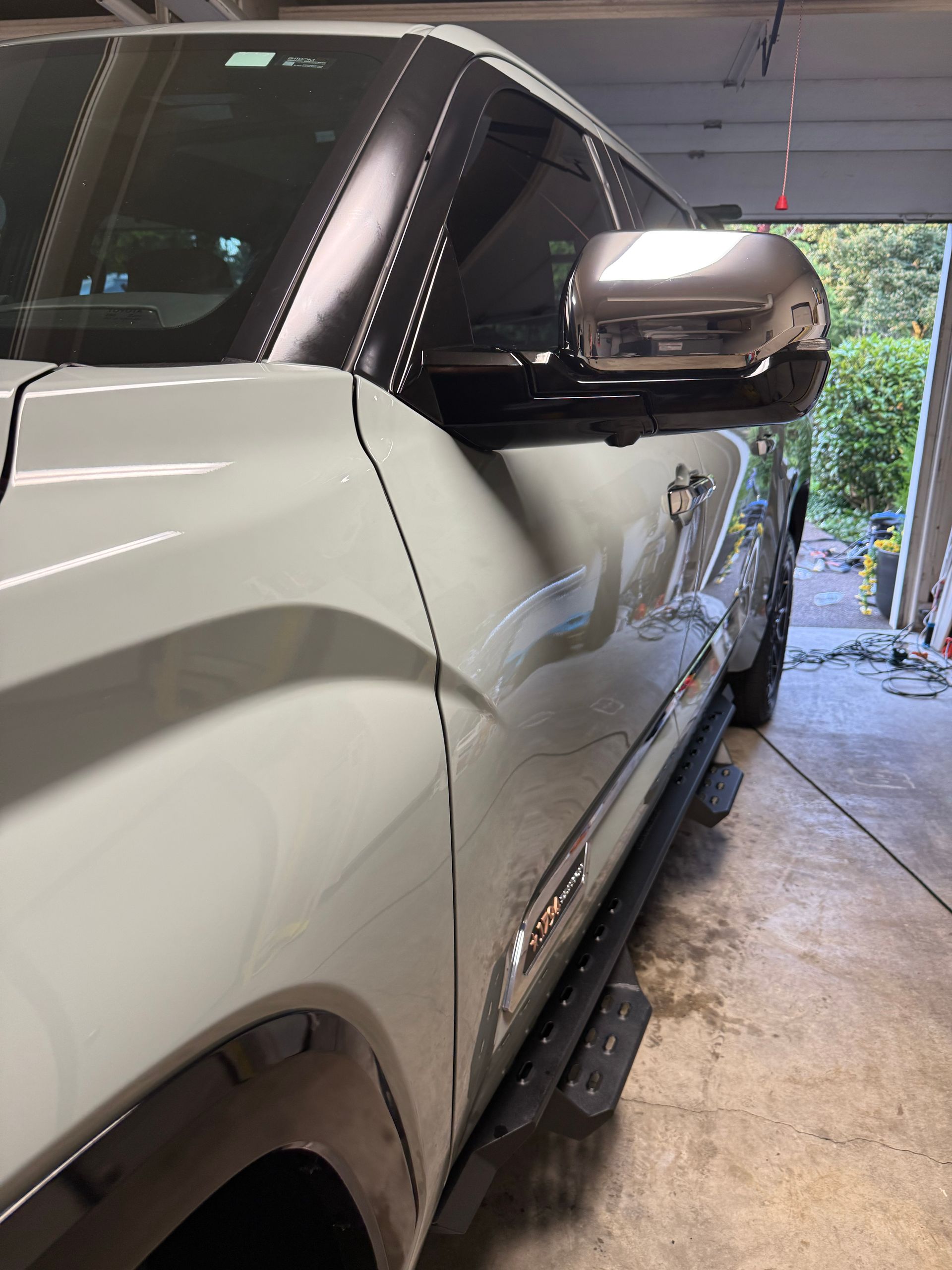 Silver SUV parked in a garage, side view with black side mirror and running board