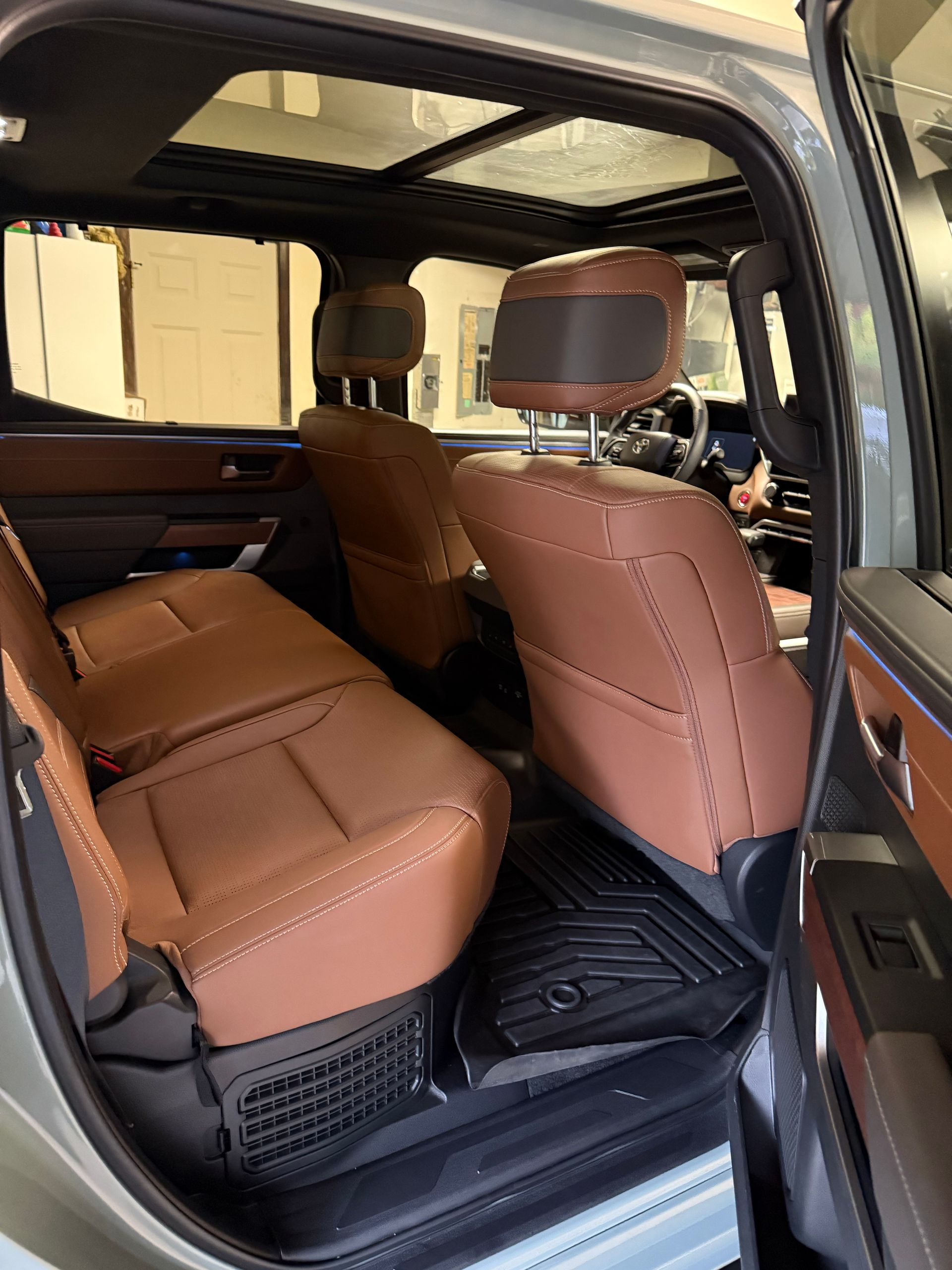 Tan leather car interior with rear seats folded and open door view