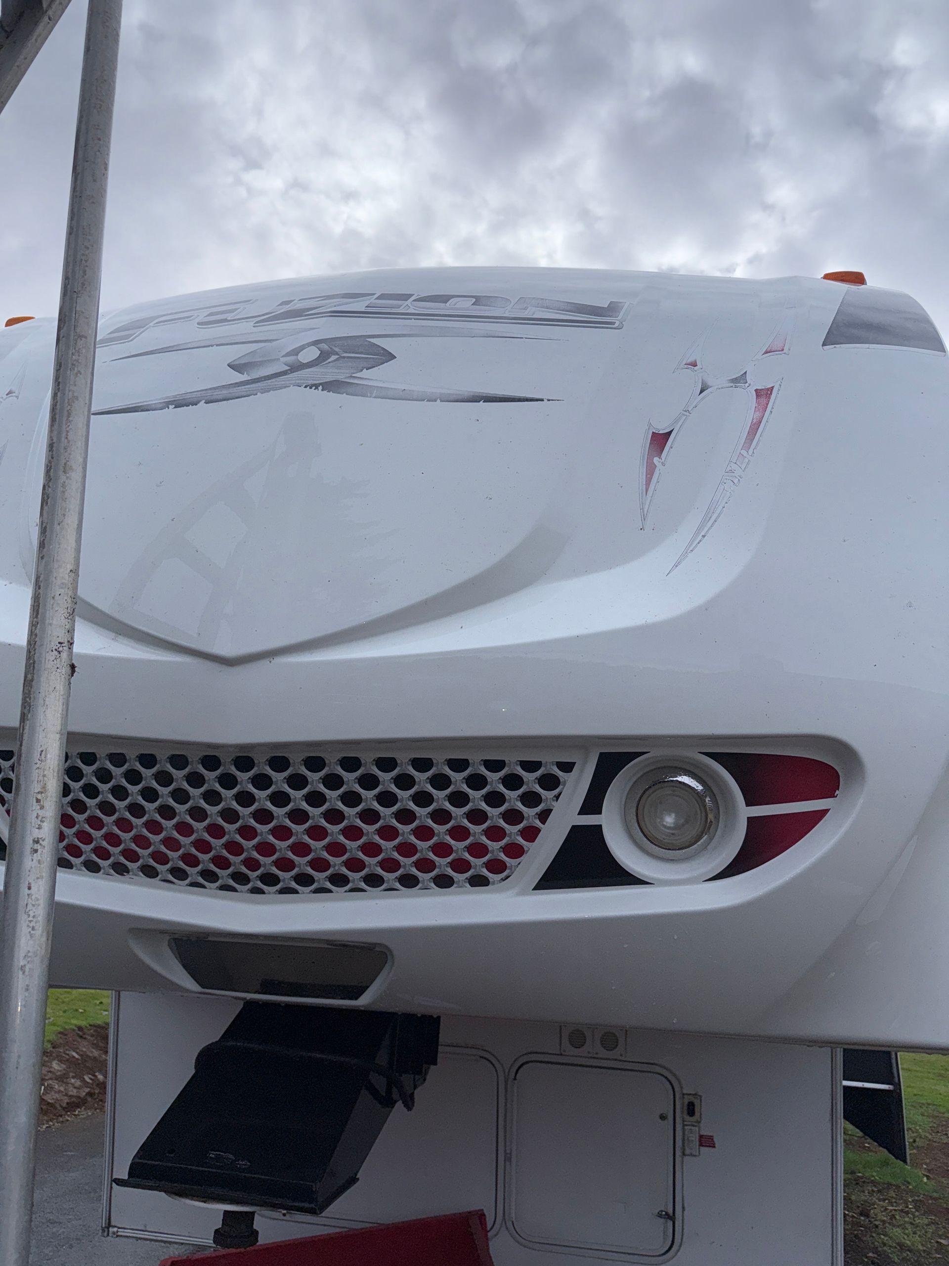 White sports car front end with snow on the hood and grille, parked in a snowy outdoor setting