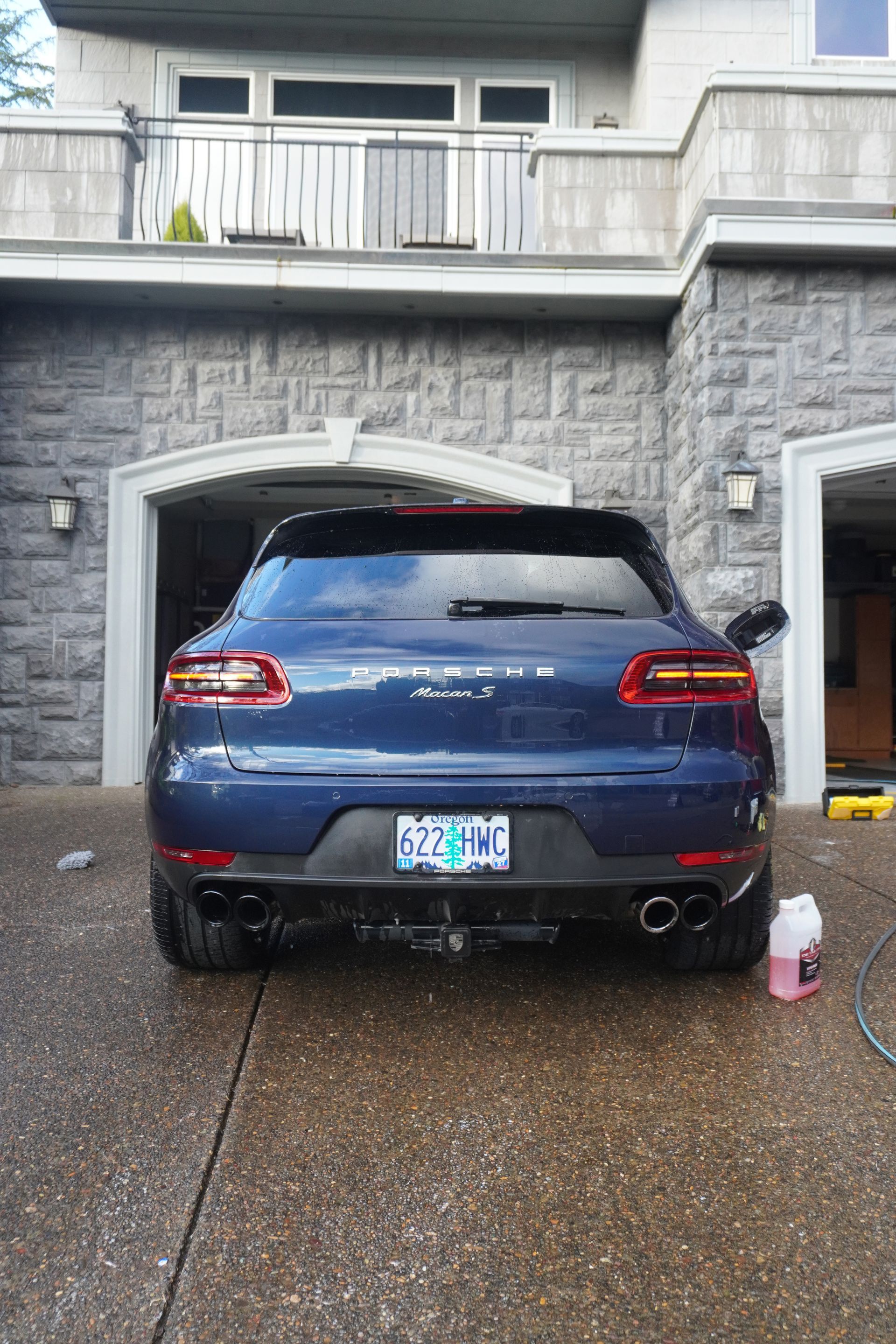 Blue SUV parked in front of a stone house on a wet driveway