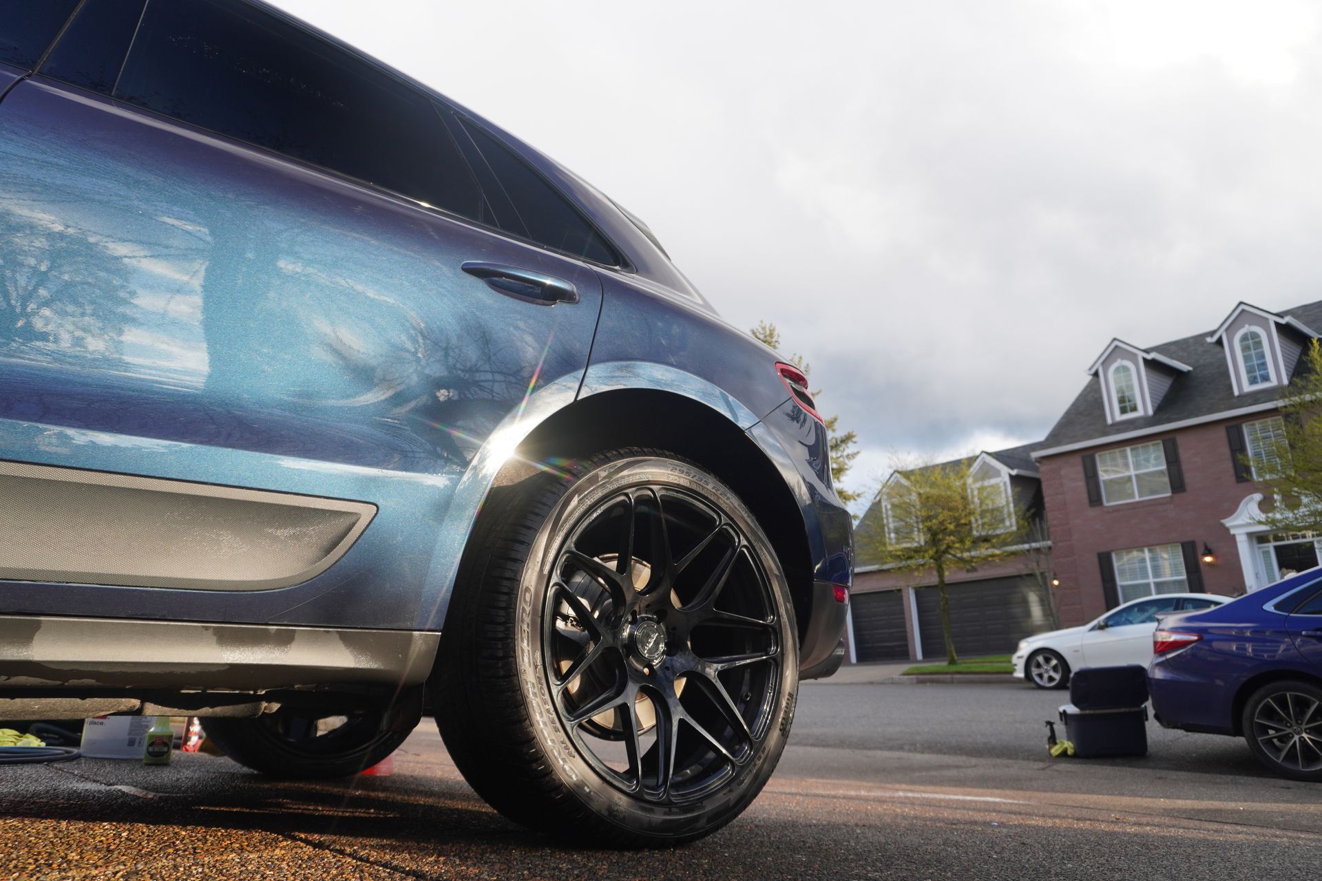 Blue SUV parked on a residential street, low-angle view of front wheel and bumper.