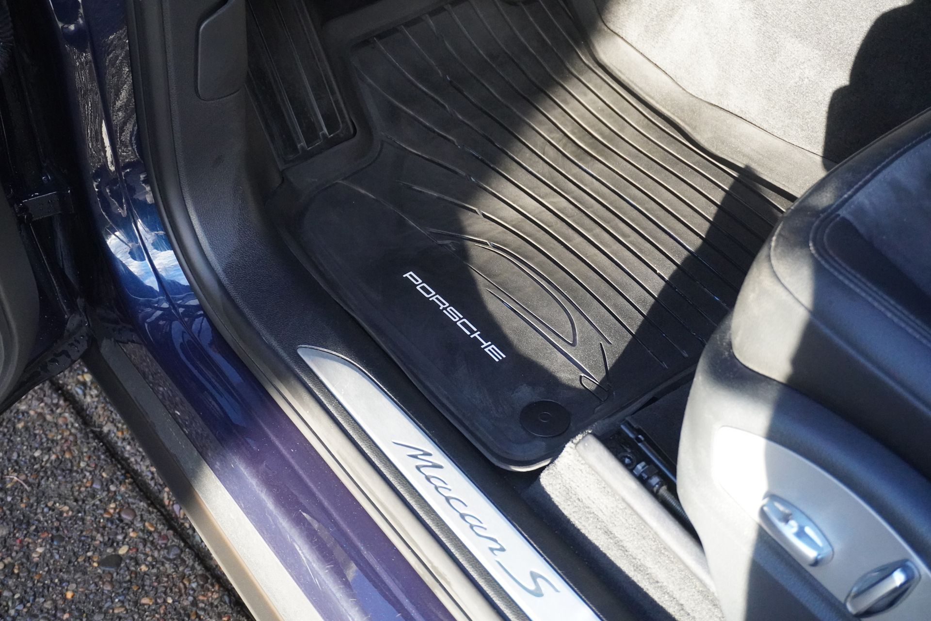 Car mat beside a car door sill with illuminated step trim and part of a blue seat visible