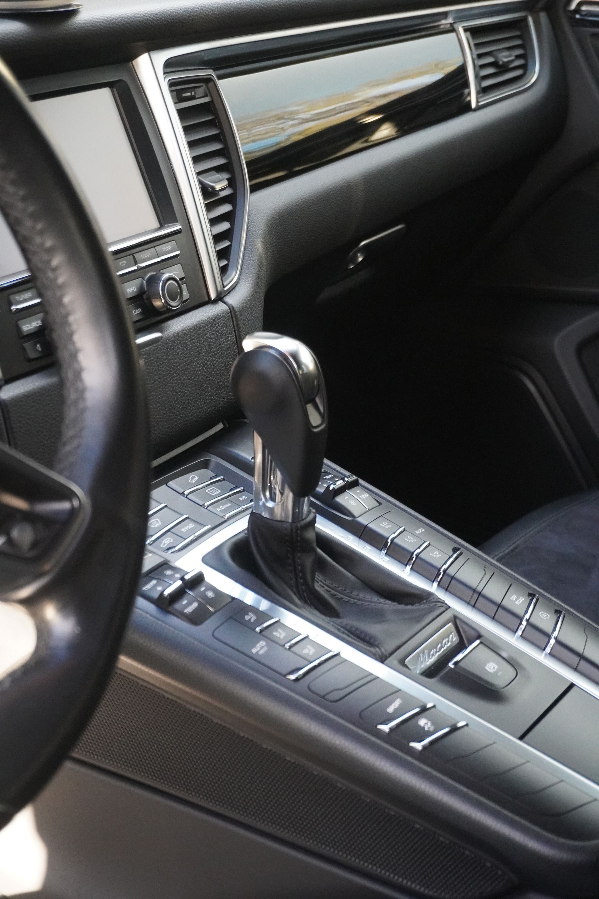 Car interior with black leather dashboard and center console, showing the gear shift and control buttons.