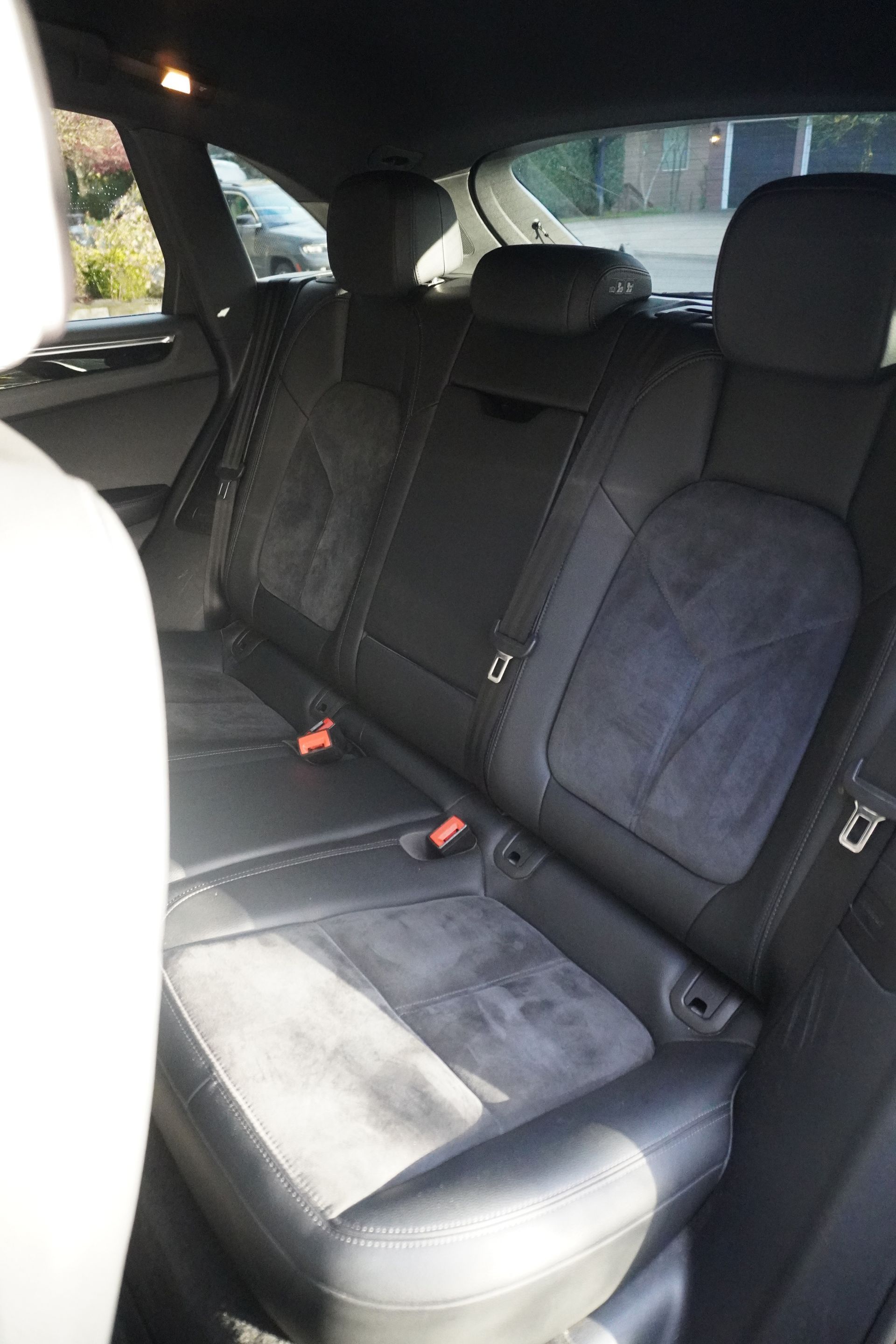 Car back seat with dark fabric upholstery and a light gray seat cushion in a parked car