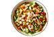 Salad with chicken, tomatoes, peppers, and bacon in a white bowl.