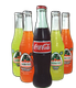 Glass soda bottles: Coca-Cola flanked by four Jarritos fruit sodas, on black background.