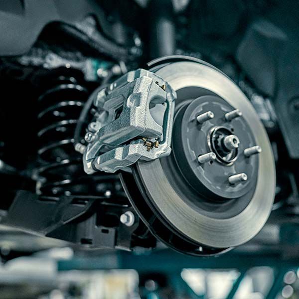 Close-up of a car brake rotor and caliper in a mechanical workshop