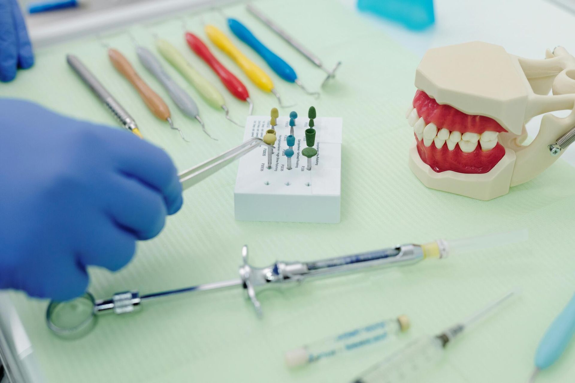 Dentist tools, gloved hand, and dental model on a clinic tray with colorful instruments