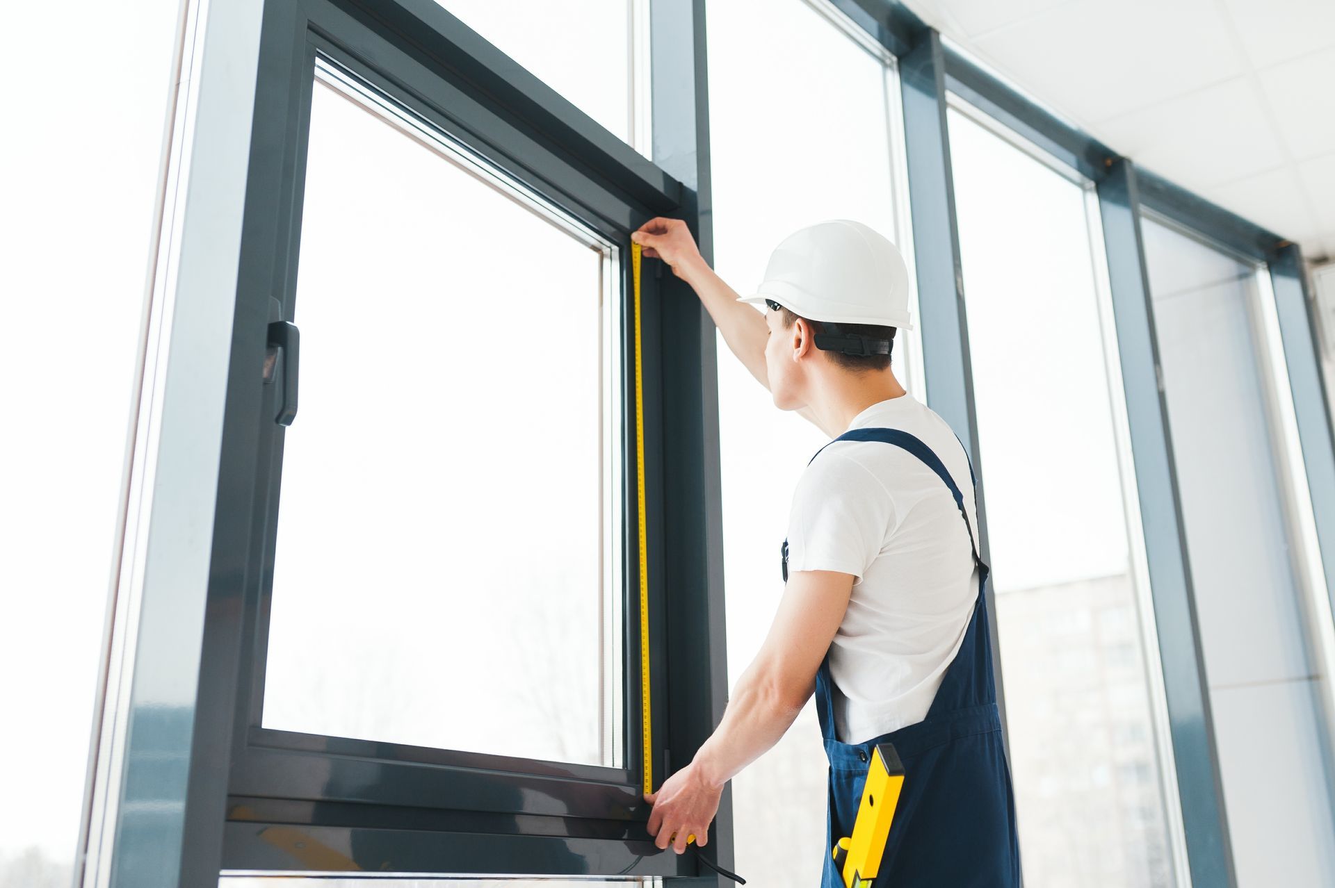 Worker installing a black window frame in a bright modern room