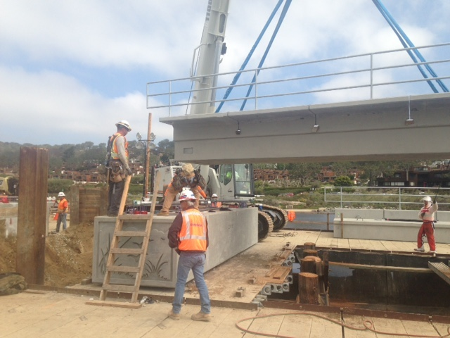 Construction crew setting a precast concrete rail girder onto its support.
