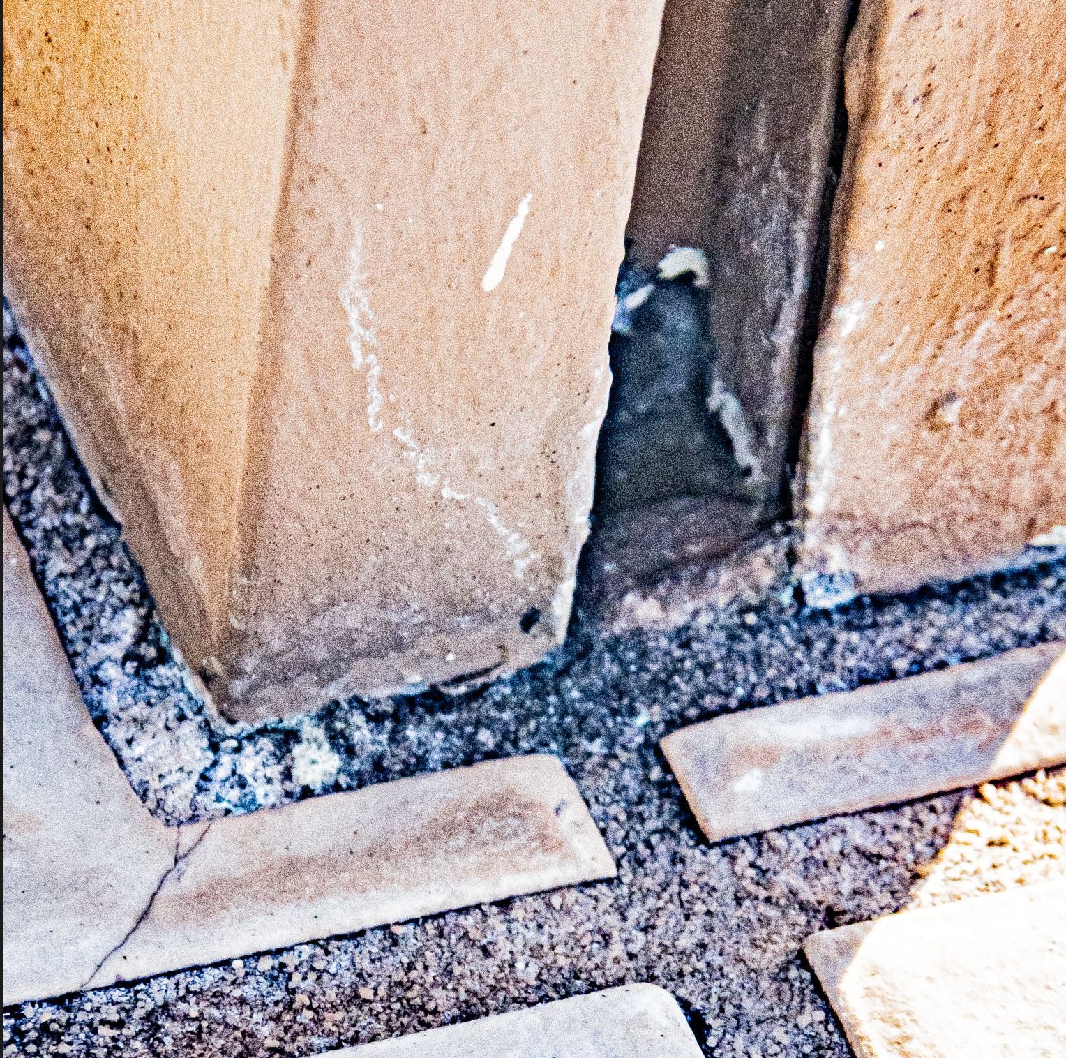 An opening between timber guardrail-post members at a tiled lanai deck exposes a water-entry path below the surface.