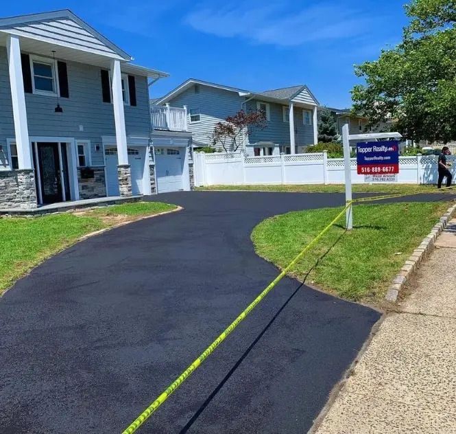 A driveway leading to a house with a sign that says for sale