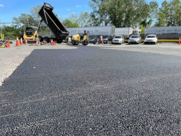 A dump truck is being loaded with asphalt in a parking lot.