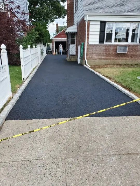 A brick house with a black driveway and a white fence