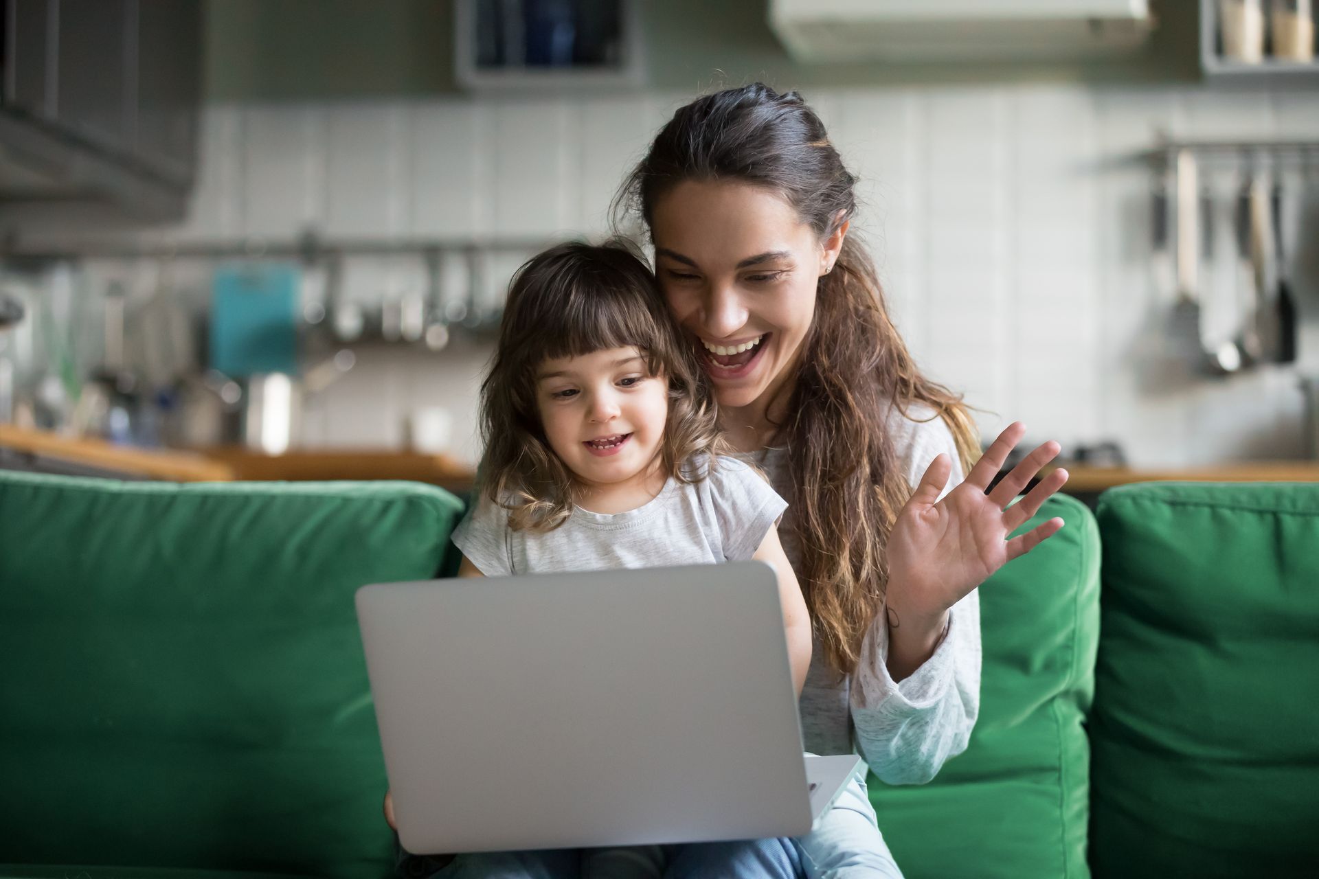 A mom and child are sitting at a table looking at a laptop computer.