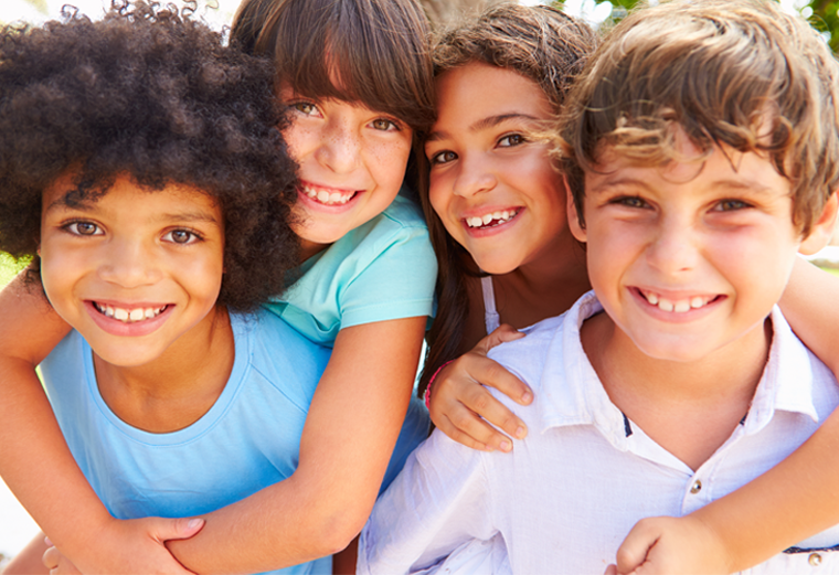 A group of children are posing for a picture together and smiling.