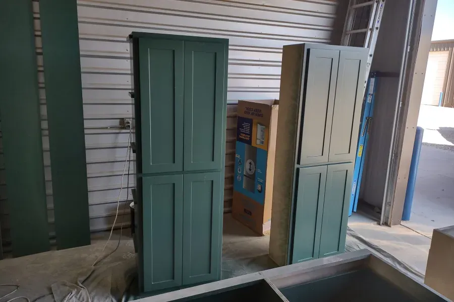 Two green cabinets are sitting next to each other in a room.