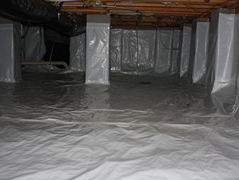 Crawlspace lined with white plastic vapor barrier under exposed wooden floor joists