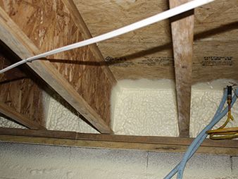 Insulated attic roof framing with exposed wooden rafters and blue cables along the right side