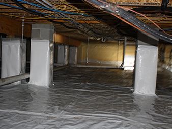 Crawlspace under a house with insulated support posts and a vapor barrier floor covering