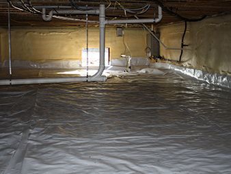 Crawlspace with plastic vapor barrier on the floor and exposed pipes and wiring overhead