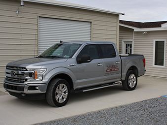Silver pickup truck parked outside a beige building with a garage door