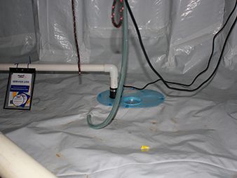 Basement floor with white sheeting, PVC pipe, black cable, blue fan, and a small yellow object