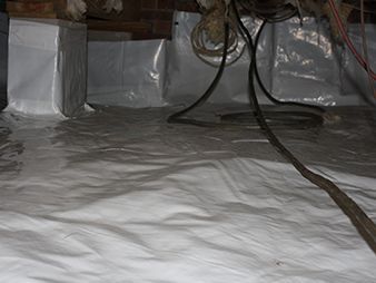 Reflective silver insulation covering a crawl space floor with exposed cables and ductwork overhead