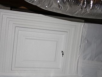White paneled cabinet door with a small keyhole, viewed at an angle.
