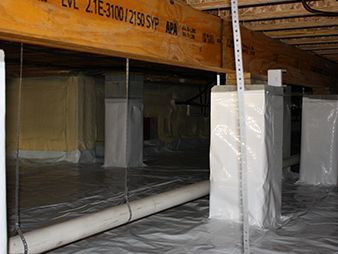 Plastic-covered support columns in an unfinished crawlspace with exposed beams and insulation