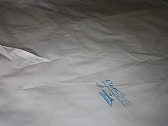 White crumpled fabric with a small blue printed logo near the center-right.