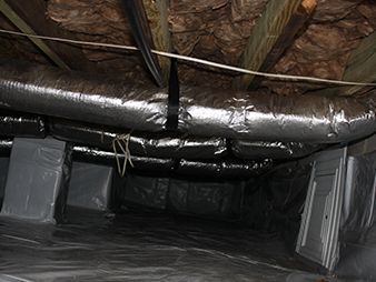 Insulated attic ductwork and vents beneath a roof, with plastic sheeting lining the floor.