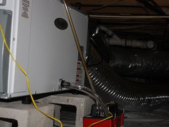 White appliance with exposed hose and yellow cord under a counter, showing a setup or repair area